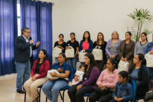 Gestantes e mães participam da entrega do Auxílio Natalidade no CRAS, ouvindo um representante enquanto seguram kits do benefício.