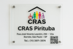 Placa de vidro do CRAS Pirituba com logotipo colorido do CRAS, endereço Rua José Vicente Leardini, 290 – Vila Barreto, São Paulo – SP, e telefone (11) 3971-3974, além de QR Code para acesso à página da unidade.