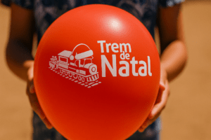 Balão do Trem de Natal segurado por criança durante ação social do CRAS em Tubarão