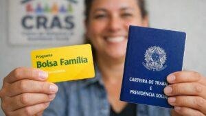 Pessoa segurando cartão do Bolsa Família e carteira de trabalho em frente ao CRAS